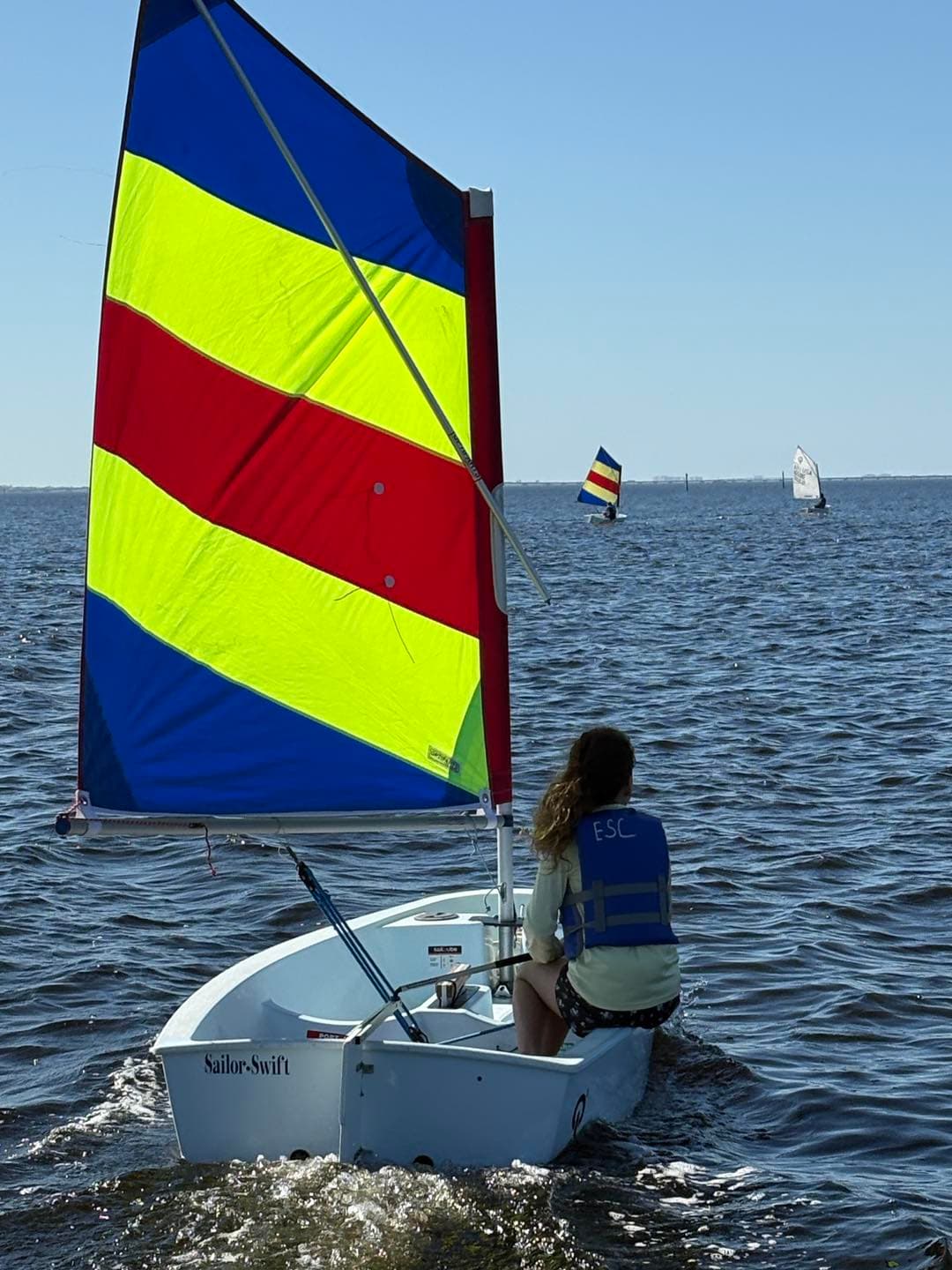 Sailor in Optimist with colorful sail