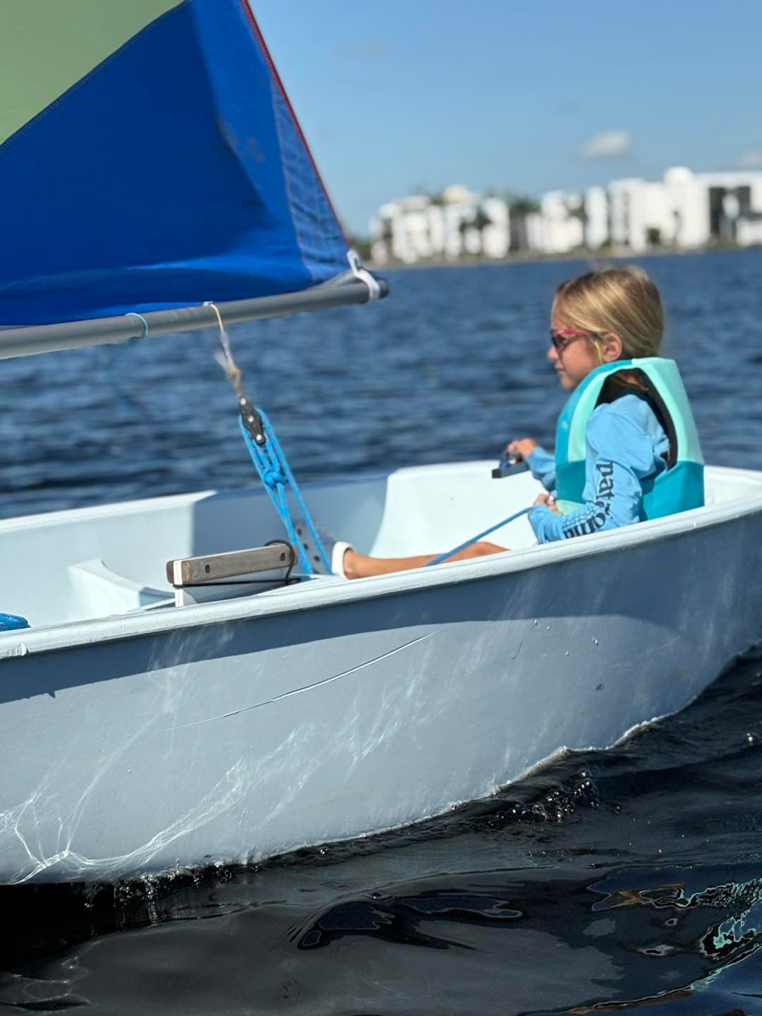 Three Optimist sailboats on a sunny day