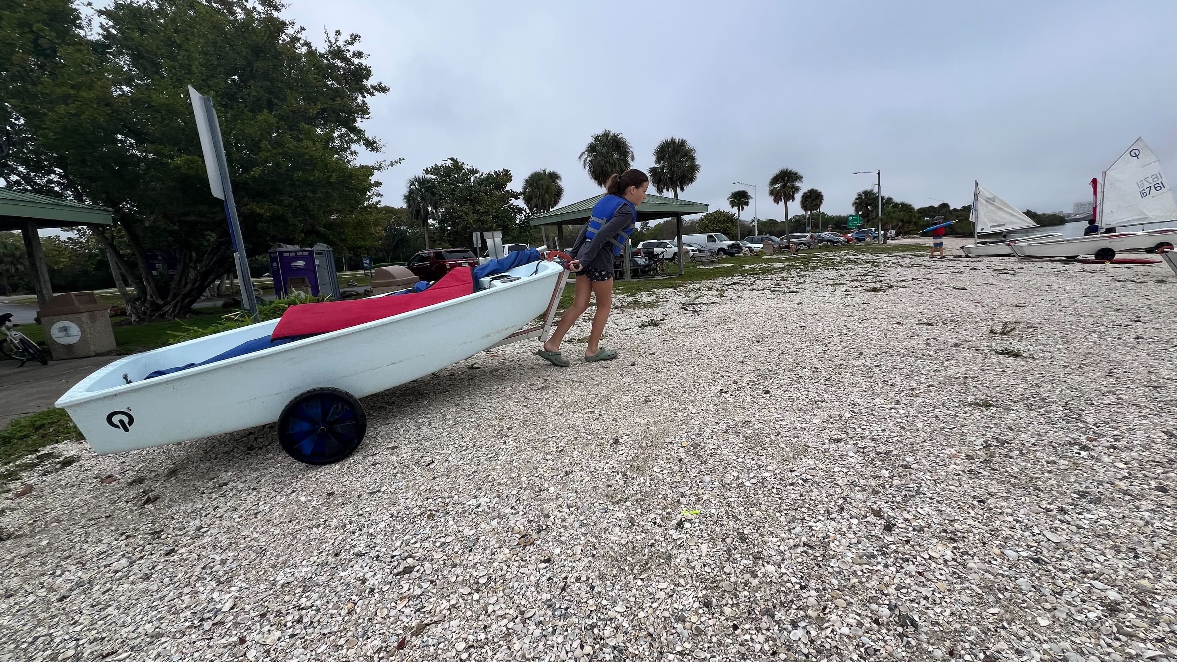 Young sailor hauling a boat on the beach