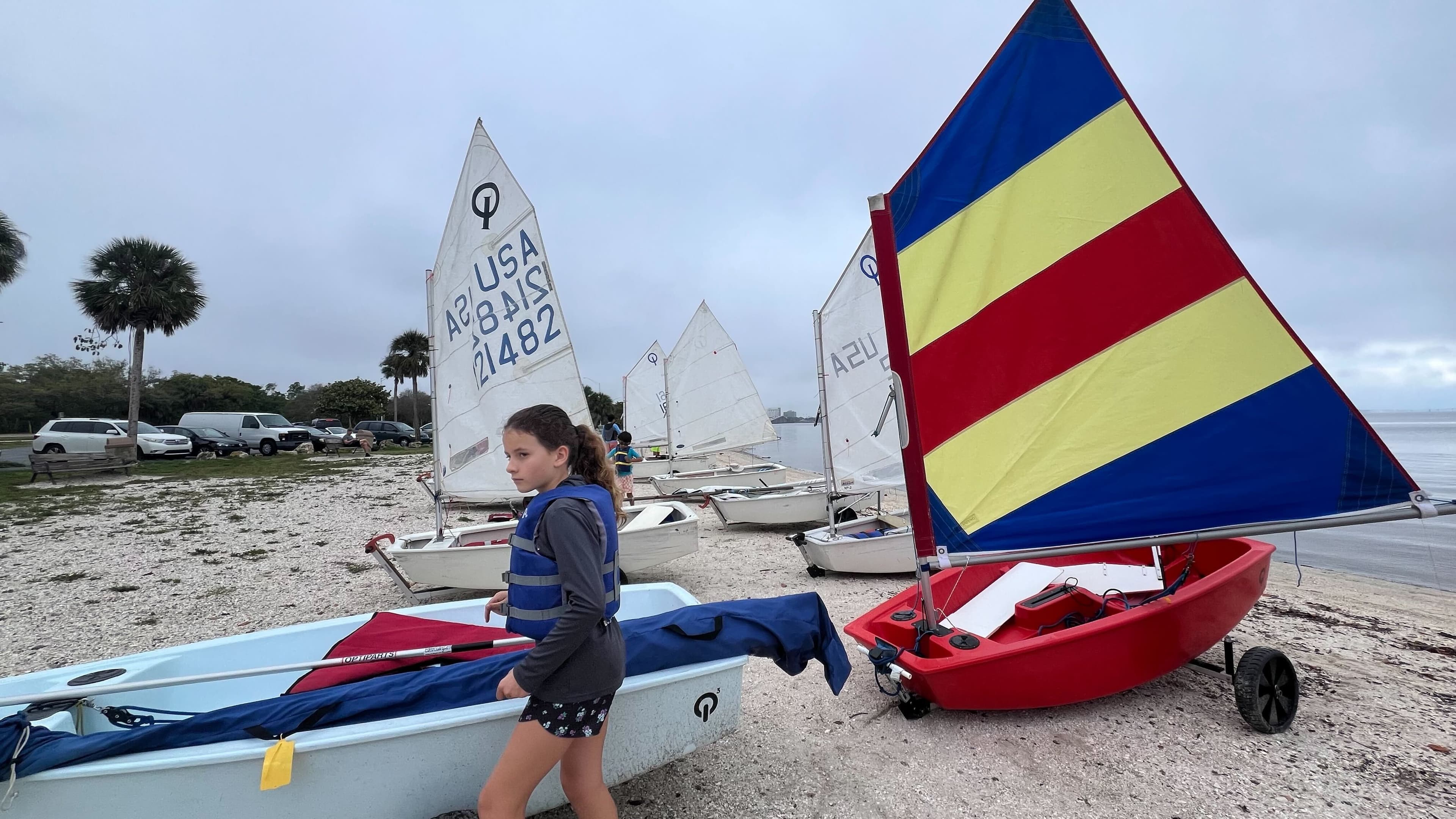 Young sailor in a life jacket with colorful sail