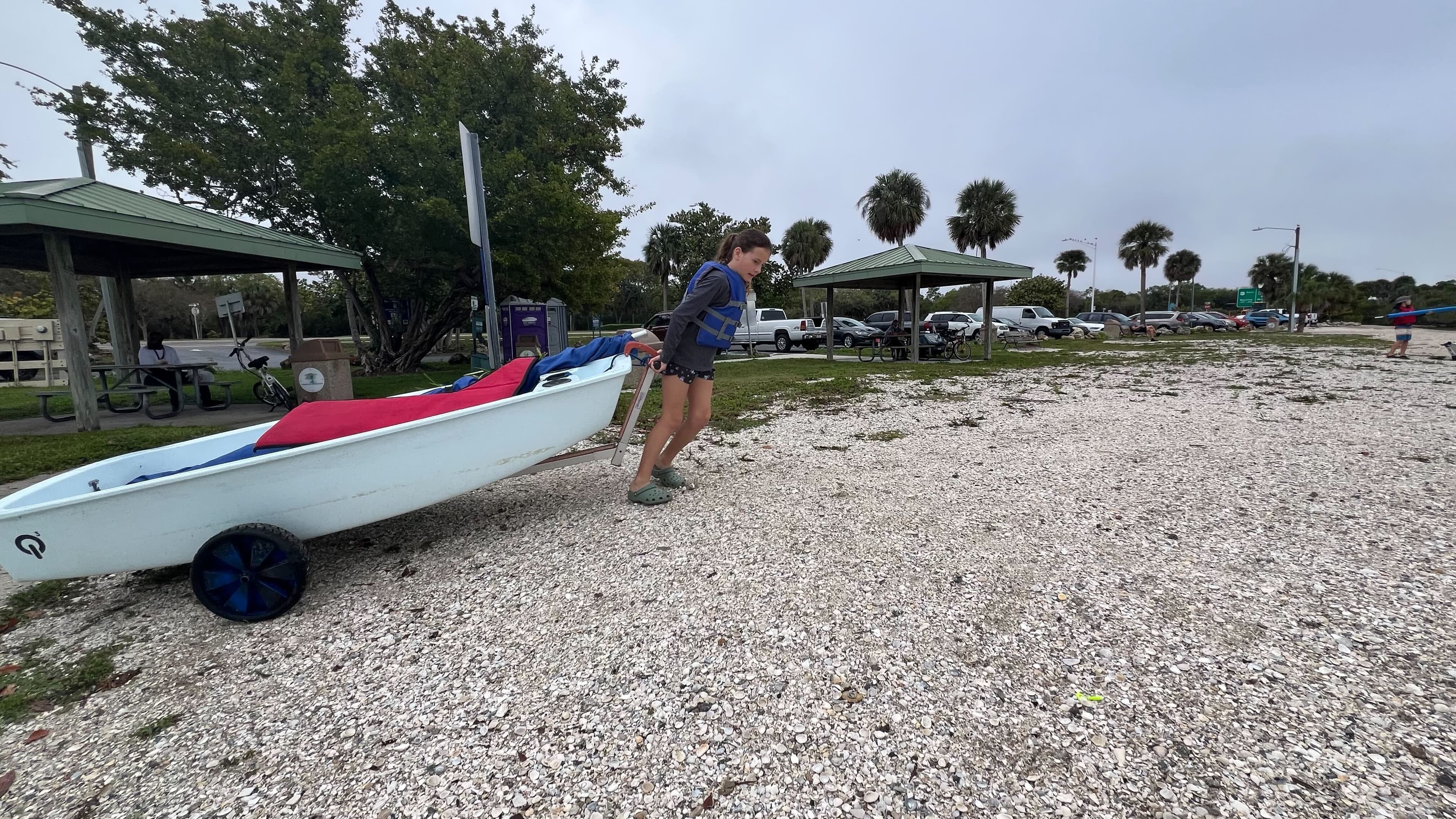 Girl pulling an Optimist through the parking area