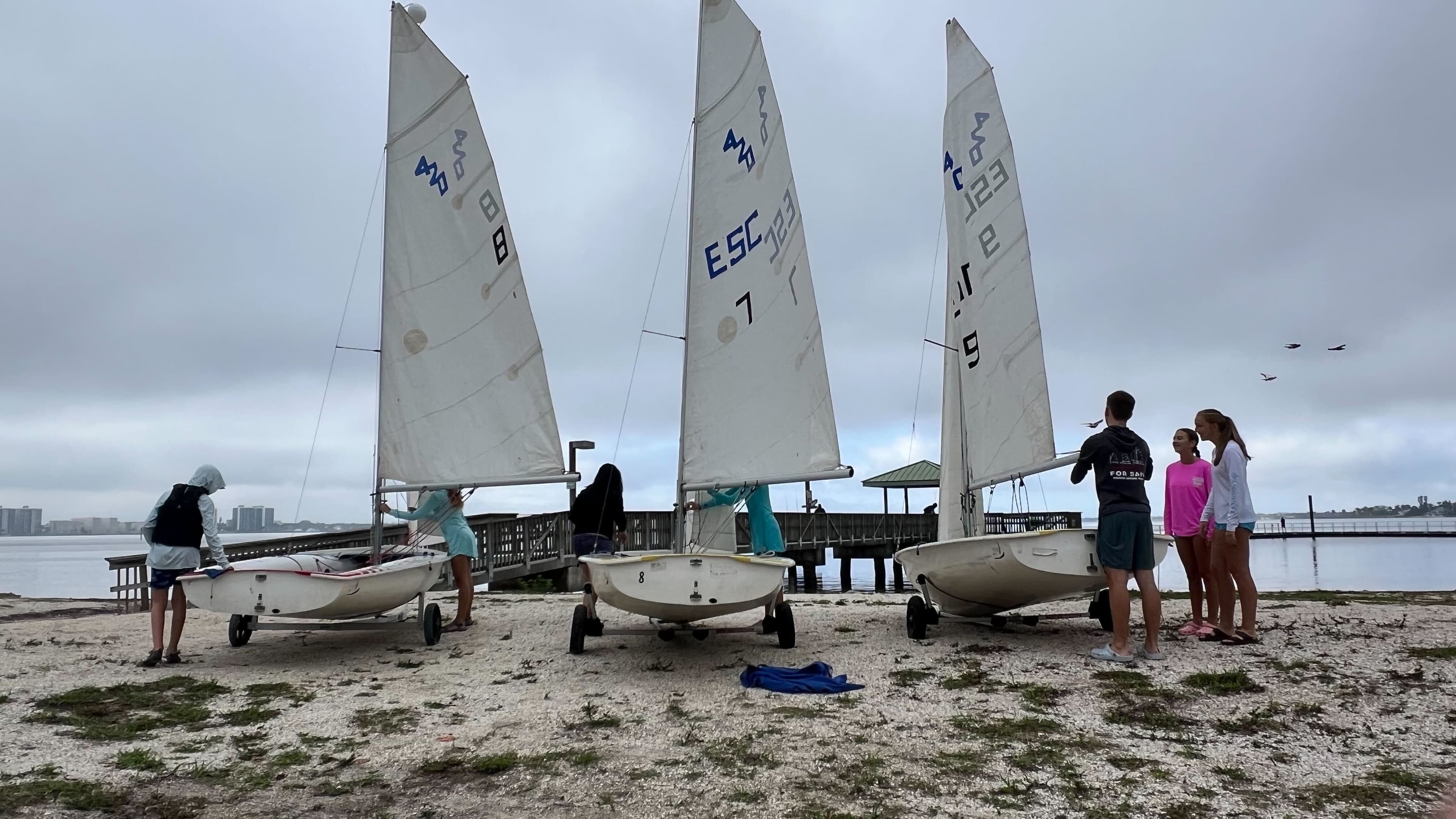 Three 420 sailboats on the beach with teens