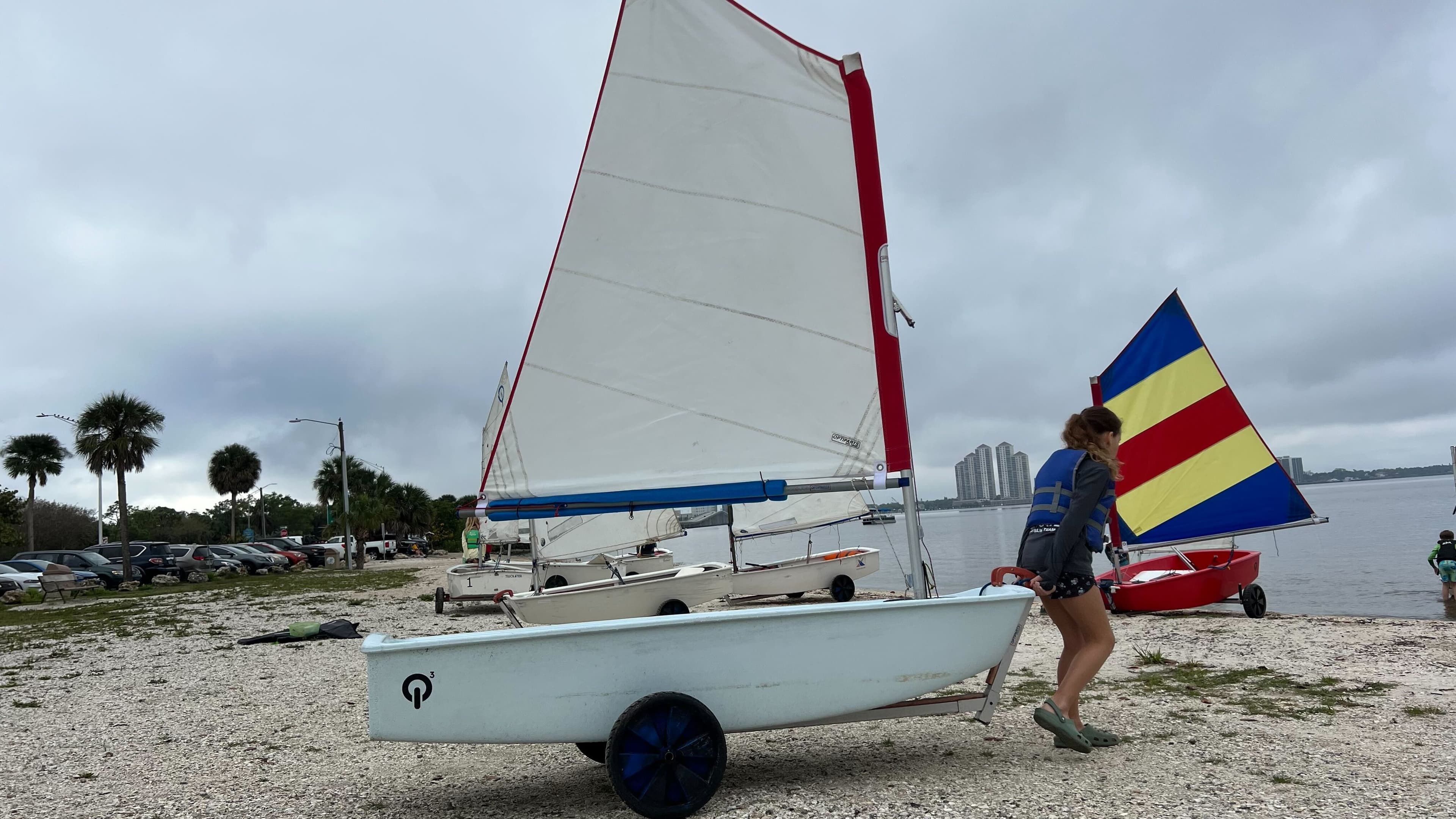 Girl pushing an Optimist on the beach