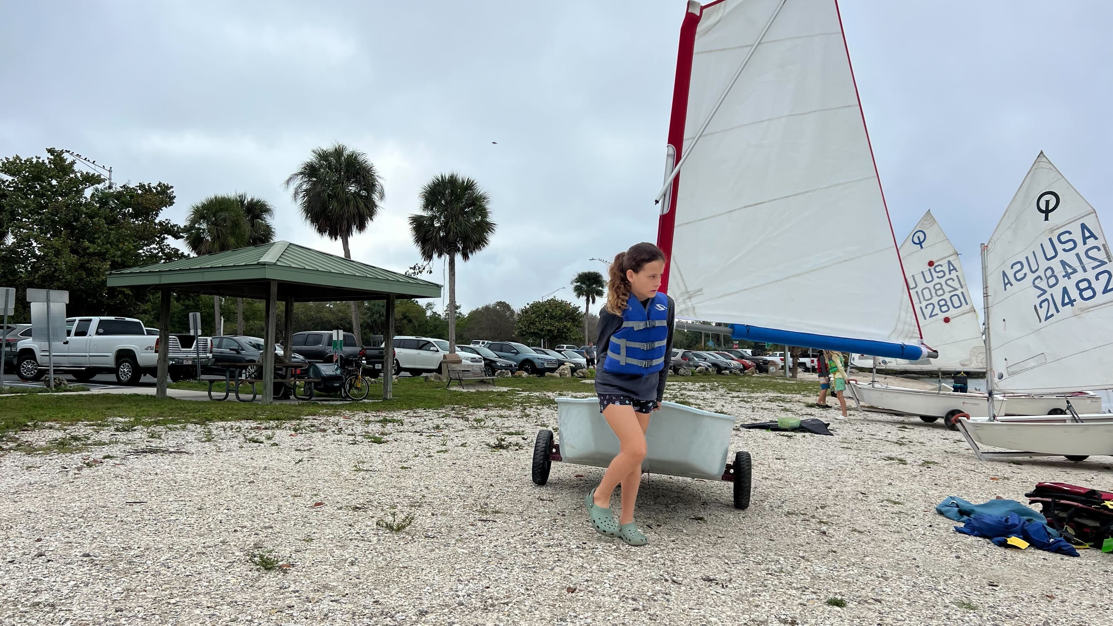 Girl sitting in an Optimist sailboat
